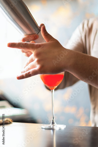 .A cocktail glass. Cooking on the counter. The bartender's hands are in the frame.