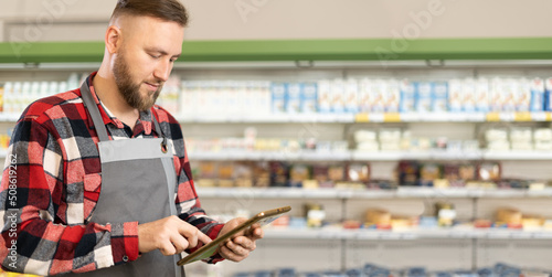 Fototapete supermarket clerk using apps on a digital tablet, young handsome supervisor with