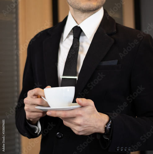 Businessman in black suit drinking coffee in office