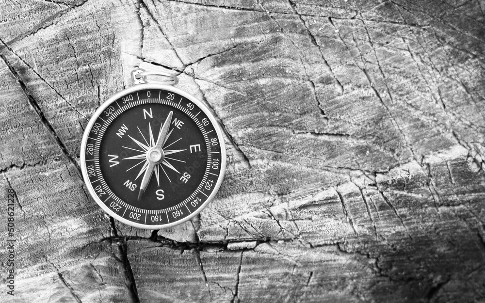 black and white photo of round compass as symbol of tourism with compass, travel with compass and outdoor activities with compass