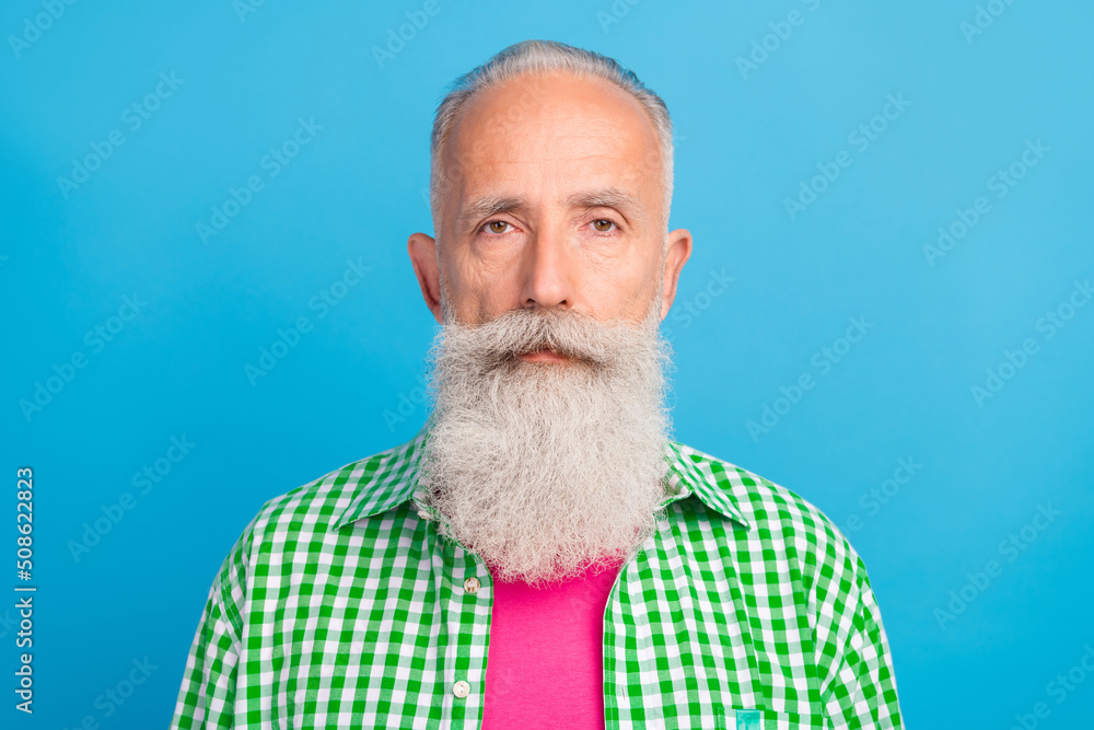 Photo of calm content aged person no emotions face look camera isolated on blue color background Photo of calm content aged person no emotions face look camera isolated on blue color background