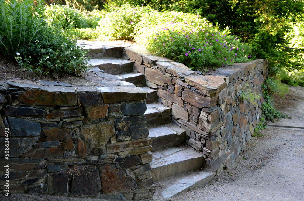 stone staircase illuminated by the morning sun. the stone is brown and joined with cement mortar. the stairs are in the rock garden or in the park