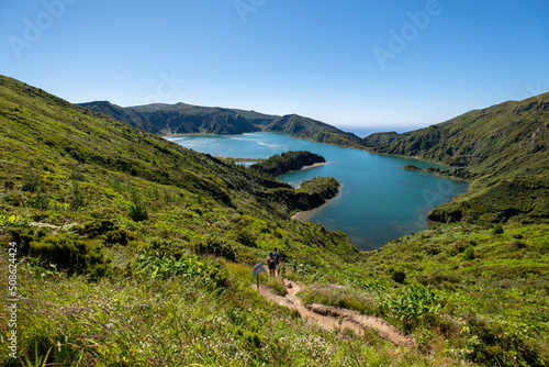 Beautiful landscape of Lake of Fire - " Lagoa do Fogo " in a sunny morning day with blue sky with a couple going down by the small path. São Miguel Island, Azores. 