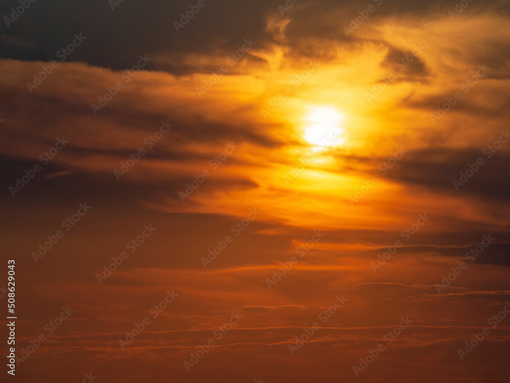 A blurry dramatic celestial sunset with clouds that the sun paints orange. Soft focus, motion is blurry. Beautiful natural background of the sunset sky