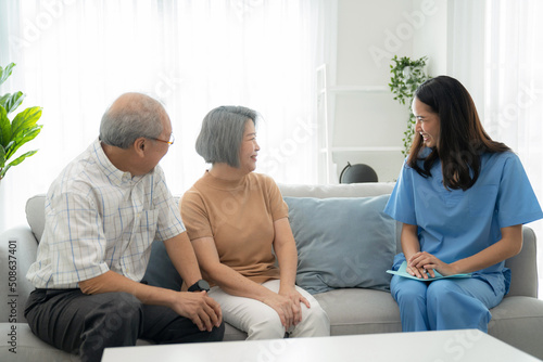 Elderly man and woman sitting on the sofa and talking with nurse at home. Attractive caregiver explain how to take care health. Asian senior with assisted living medication monitoring concept photo