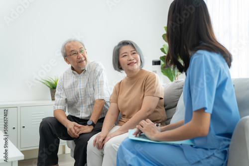 Elderly man and woman sitting on the sofa and talking with nurse at home. Attractive caregiver explain how to take care health. Asian senior with assisted living medication monitoring concept photo