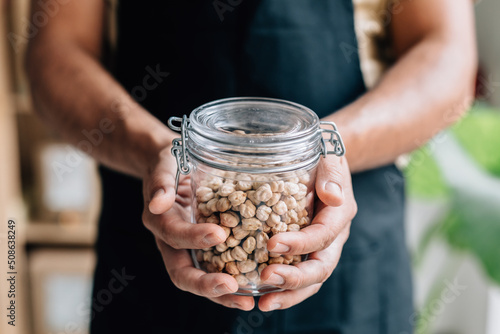 Shopkeeper holding glass jar with chickpeas