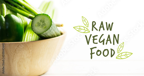 Image of raw vegan text in green over bowl of fresh organic vegetable salad on wooden boards