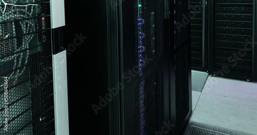 Image of empty corridor with rows of computer servers with green and purple lights