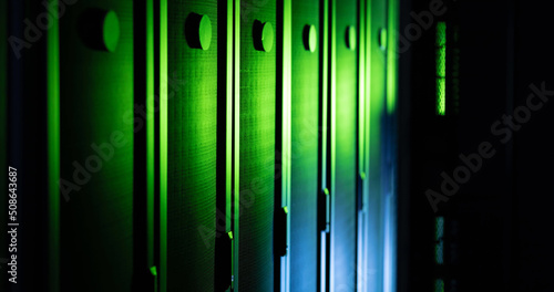 Image of close up of empty corridor with row of blue and green computer servers