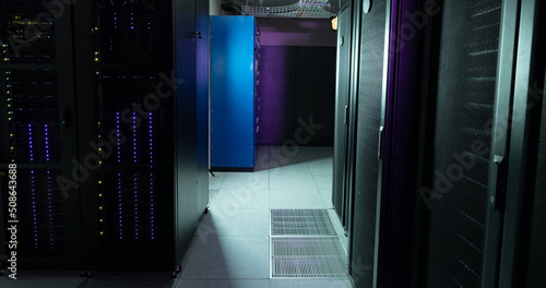 Image of empty corridor with rows of purple and blue computer servers