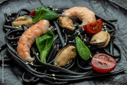 Pasta black spaghetti with prawn and mussels seafood. on dark background. Black spaghetti. banner, menu, recipe place for text, top view