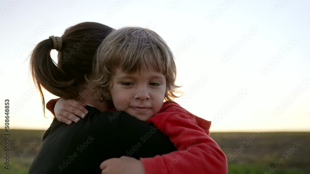 Loving smiling son hugs mom tightly. Tender family scene. Cute 3 year old kid with mother. Parenthood, childhood, happiness, children wellbeing concept. Loving smiling son hugs mom tightly. Tender family scene. Cute 3 year old kid with mother. Parenthood, childhood, happiness, children wellbeing concept.