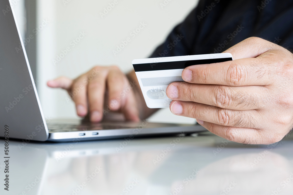 Male hands holding credit card and using laptop. Online shopping concept photo with copy space area.