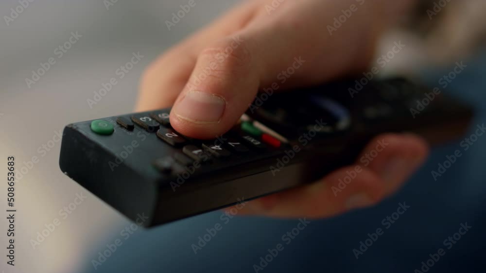 Fingers pushing remote control buttons closeup. Unknown man switching channels. Fingers pushing remote control buttons closeup. Unknown man switching channels.