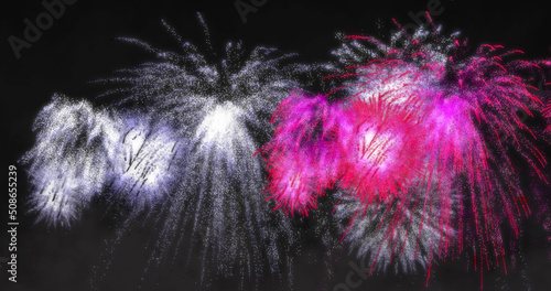 Image of pink and white christmas and new year fireworks exploding in night sky
