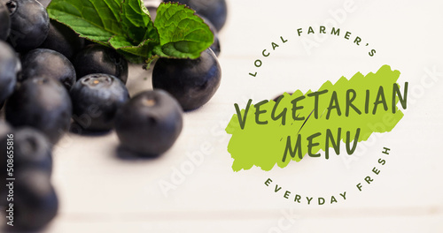 Image of vegetarian menu text in green over fresh organic blueberries