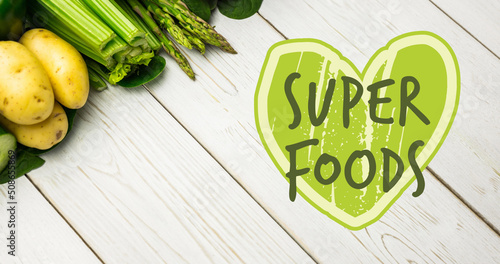 Image of super foods text in green over fresh organic vegetables on wooden boards