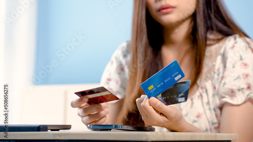 Beautiful Asian girl, Beautiful Asian girl, wearing a white floral shirt, is paying online for an order via a laptop computer, with a credit card in his hand,online shopping.