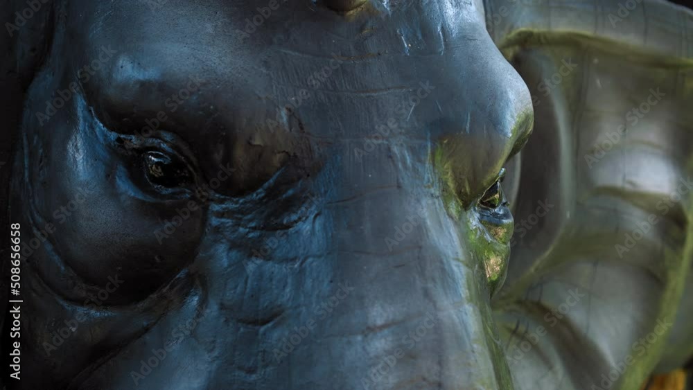 elephant statue face closeup with blue and green shades on the skin