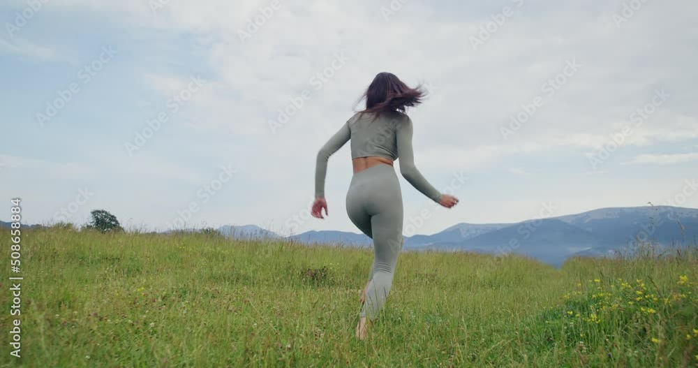 Carefree young woman in activewear walking among green grass during summer time. Concept of people, freedom and lifestyles. Carefree young woman in activewear walking among green grass during summer time. Concept of people, freedom and lifestyles.