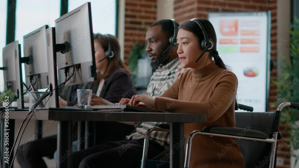 Young woman working at customer assistance service, using microphone on headphones. Female worker talking to clients at call center, helping with remote telemarketing problems. Handheld shot. people Young woman working at customer assistance service, using microphone on headphones. Female worker talking to clients at call center, helping with remote telemarketing problems. Handheld shot. people