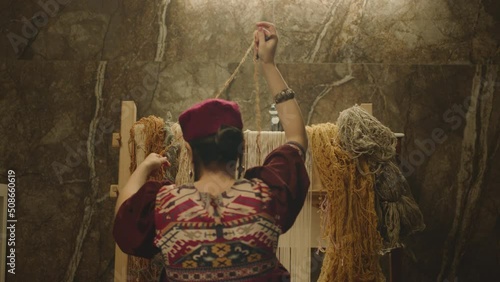 A Woman weaving traditional Asian carpet . Handmade carpet embroidery . Back view of Woman create a pattern using multi-colored threads . Rear view . Weaving machine . Needlework . Carpet-makers 