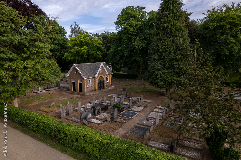 Small cemetery seen from above with greenery park and hedge surrounding it