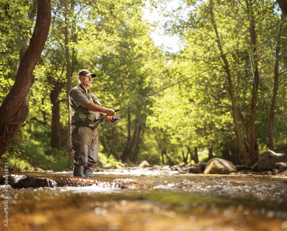 Man fishing on a river surrounded by trees Man fishing on a river surrounded by trees
