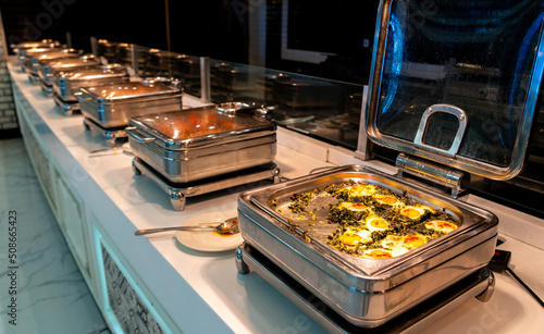 All-inclusive buffet food in heating trays in hotel restaurant with eggs with spinach for breakfast