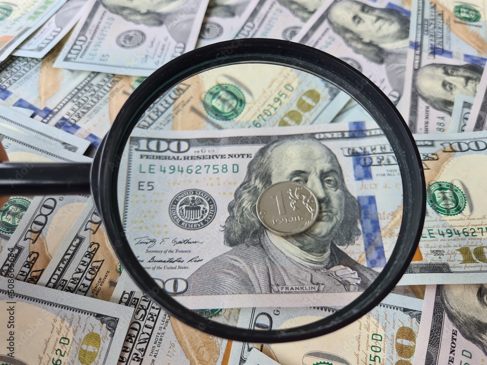 Ruble coin with a magnifying glass against background of dollars economic crisis in Russia Ruble coin with a magnifying glass against background of dollars economic crisis in Russia