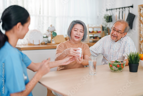 Young asian female caregiver talking to an elder couple at home.