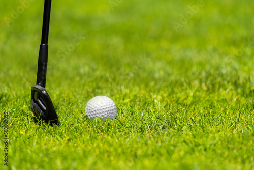 Golf ball and golf club on green grass on golf course