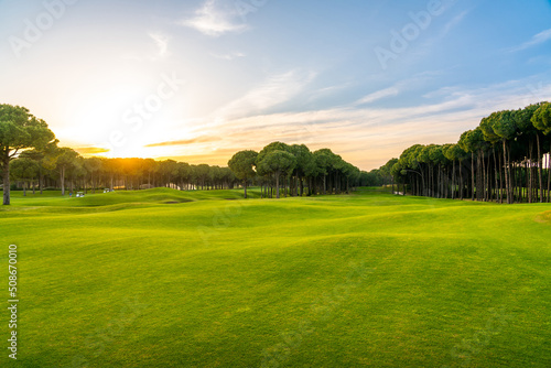 Scenic panoramic view of Golf course at sunset with beautiful sky. Golf fairway with pines photo