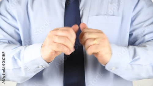 A man in a blue shirt and tie cracks the knuckles of his hands and fingers, demonstrating knuckle-cracking or knuckle joints. Medical Concept photo