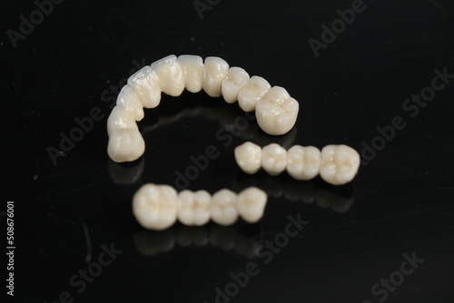 Dental ceramic bridge on isolated wite background. Metal free ceramic dental crowns.  Closeup ceramic to dental implants in laboratory.