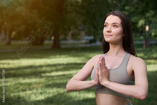 Portrait of a happy young woman practicing yoga in the park on a summer day.