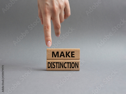 Make distinction symbol. Concept words make distinction on wooden blocks. Beautiful grey background. Businessman hand. Business and make distinction concept. Copy space.