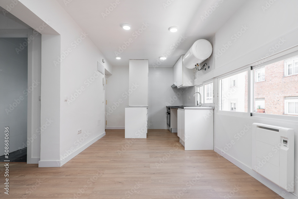 Fototapeta premium Kitchen with newly installed cabinets in simple apartment with light wood floors and a wall full of narrow windows with a view