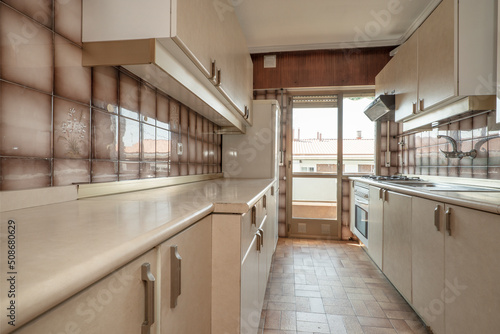 Print op canvas Apartment kitchen with beige furniture with matching stoneware floors and access