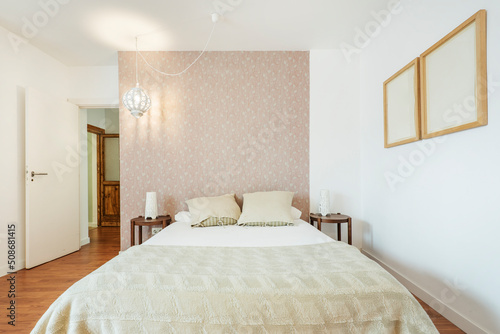 Double bedroom with round wooden bedside tables, wall with decorative wallpaper and wooden floors