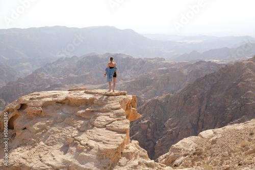 Silhouette of standing woman on rock at beautiful mountain viewpoint. Views of mountain range from Tafilah Highway, Dead Sea depression in the background. Jordan. photo