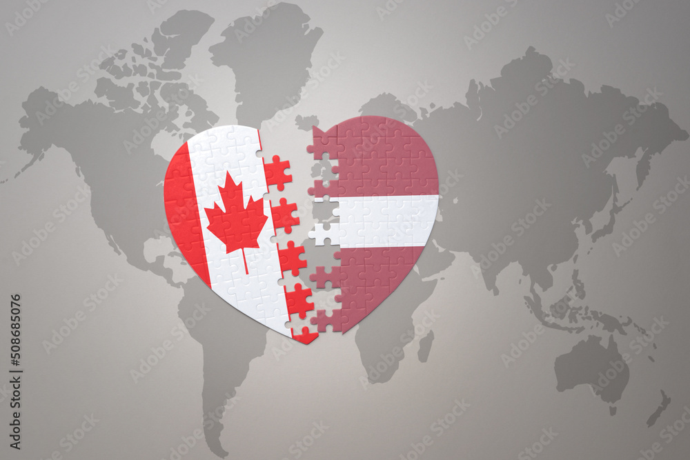 puzzle heart with the national flag of canada and latvia on a world map background.Concept. puzzle heart with the national flag of canada and latvia on a world map background.Concept.
