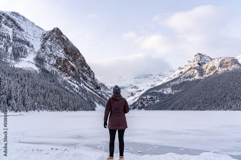 Lake Louise, Alberta, Canada - Woman tourist standing beside the stunning tourist area in winter time. 