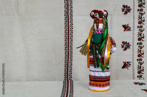 Traditional Ukrainian folk dolls motanka, handmade doll in folk costume, against the background of home-woven embroidered canvas. Culture of Ukraine, folk crafts photo