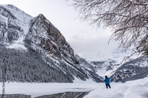 Lake Louise, Alberta, Canada - Man tourist standing beside the stunning tourist area in winter time.  photo