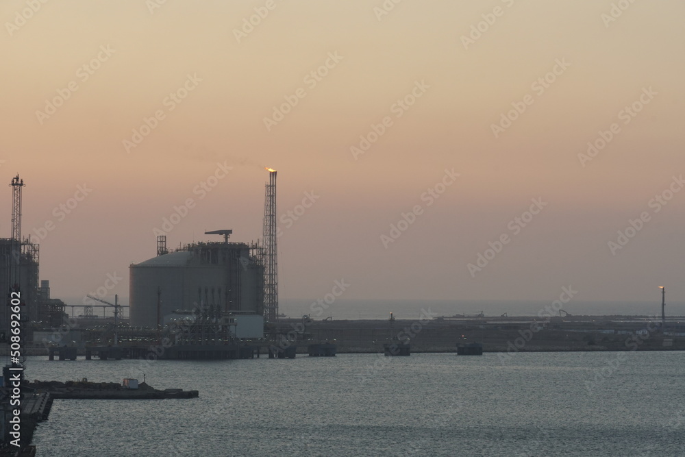 View on Damietta Segas LNG Terminal which is an export terminal belong to Spanish Egyptian Gas Company during sunset. On the horizon is orange sky with copy space.