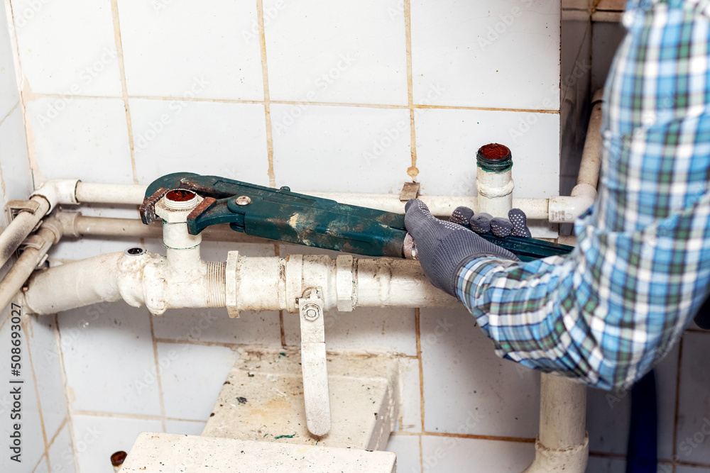 Worker uses an adjustable wrench to tighten the nut on the pipe of the