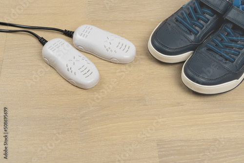 Electric ultraviolet shoe dryer for footwear with sneakers on the floor, copy space.