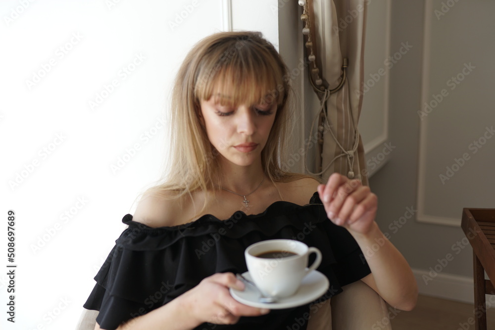 In the photo, the girl is drinking coffee at her balcony. A man takes a picture of her, she is enjoying the morning and breakfast In the photo, the girl is drinking coffee at her balcony. A man takes a picture of her, she is enjoying the morning and breakfast